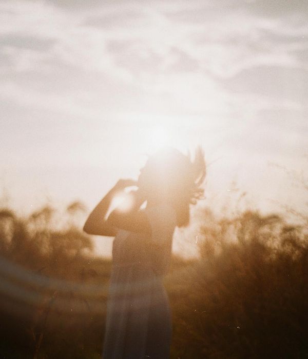 A serene woman meditating with a gentle smile, surrounded by soft light.